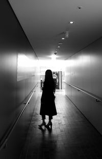 Rear view of woman walking on illuminated corridor