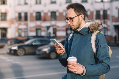 Young man using mobile phone in city