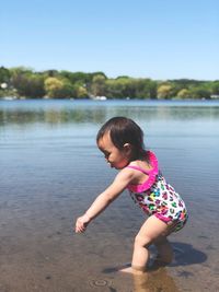Side view of baby girl standing in lake