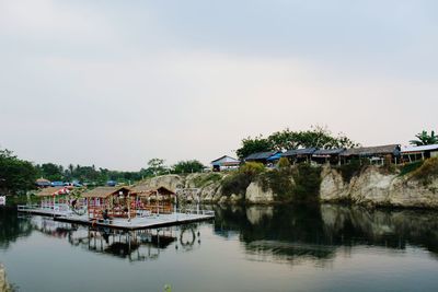 Bridge over river by buildings against sky