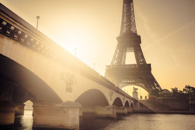 Pont d iena bridge over seine river by eiffel tower against sky during sunset