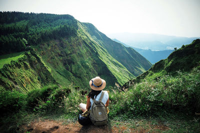 Full length of man sitting on landscape against mountains