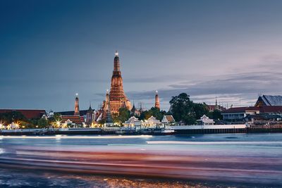 Chao phraya river against bangkok skyline with temple wat arun at dusk. capital city of thailand.