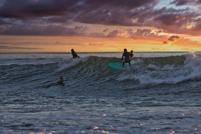 People on sea against sky during sunset