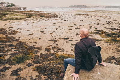 Rear view of man sitting at beach