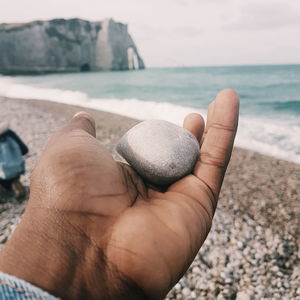 Midsection of person hand on rock at beach