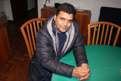 Portrait of young man sitting on table at home