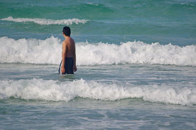 Rear view of shirtless man in sea