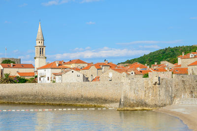Buildings by river against sky