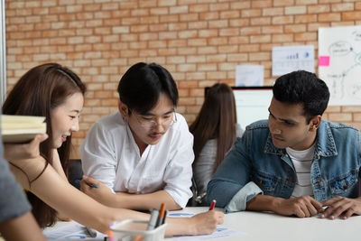 Young couple looking at people sitting on table