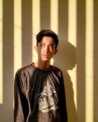 Portrait of young man standing against wall