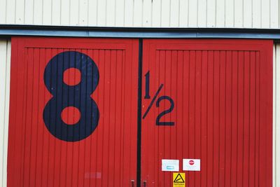 Low angle view of numbers on red metallic door