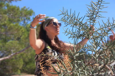 Low angle view of woman on plant against sky