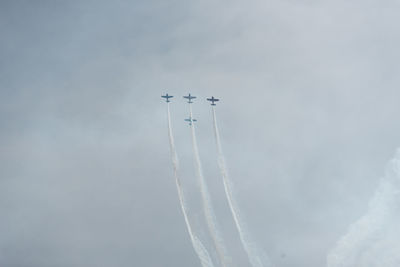 Low angle view of airplanes flying against sky during air show