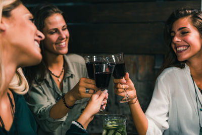 Female friends toasting wineglasses at outdoors restaurant during night