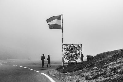 Rear view of people walking on road against sky