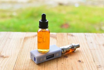 Essential oil in bottle over electronic cigarette on table