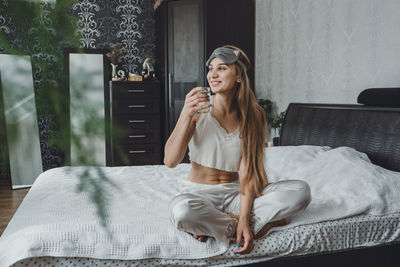 Young woman sitting on bed at home