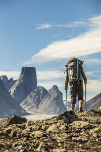 Rear view of man standing on rock against sky