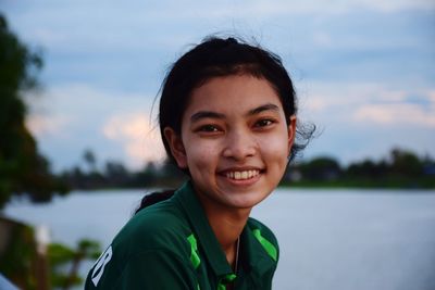 Portrait of smiling girl sitting by lake