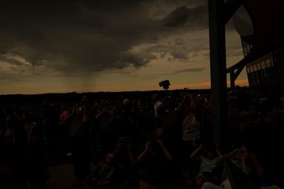 Crowd at music concert against sky during sunset