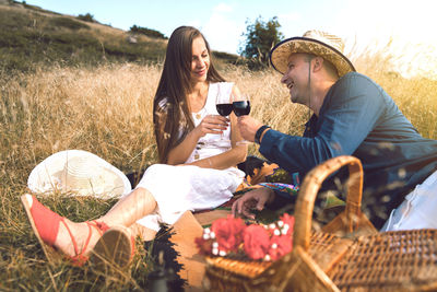 Couple toasting wineglasses while sitting on land