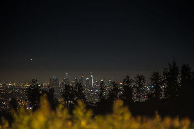 Illuminated buildings in city against sky at night