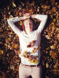 High angle view of smiling young woman with autumn leaves