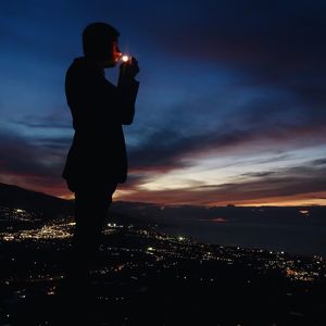 Silhouette of woman looking at city at dusk