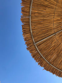 Low angle view of parasol against clear blue sky