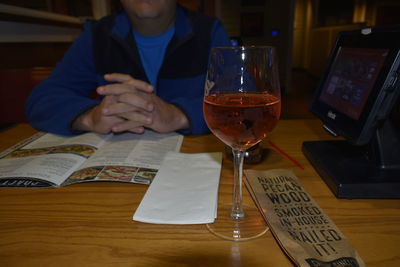 Midsection of man holding wine glasses on table at restaurant