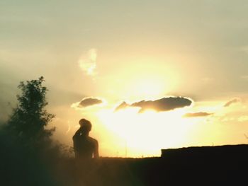 Silhouette man standing on field against sky during sunset
