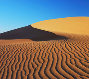 Scenic view of sand dunes against clear sky