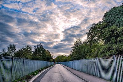 Empty road amidst trees against sky