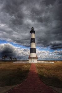 Lighthouse at beach against sky