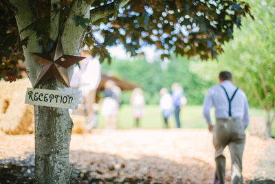 Sign board on tree with people in background at reception