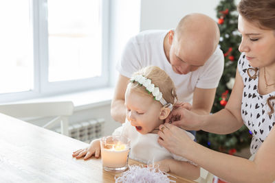 Parents dressing up daughter at home