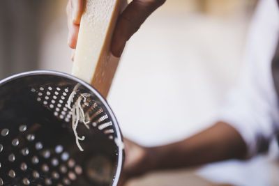 Cropped image of woman hands grating cheese in kitchen