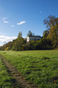 House on field by trees against sky