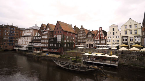 Boats in river in city against sky