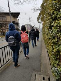 Rear view of people walking on footpath