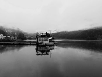 Hut reflection in lake at baselga di pine against cloudy sky
