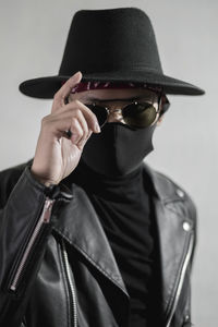 Portrait of man wearing sunglasses standing against wall