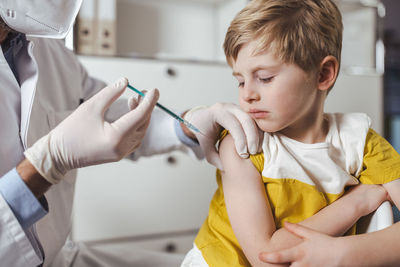 Boy getting vaccinated by doctor at center
