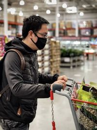 Full length of young man looking away while standing in store