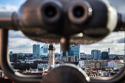 Close-up of coin-operated binoculars against buildings in city