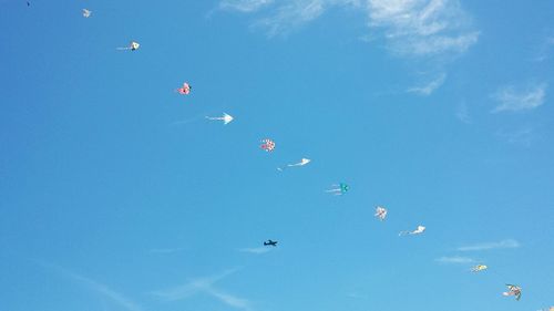 Low angle view of kites in blue sky