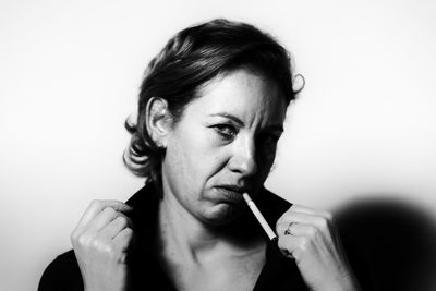 Portrait of mid adult woman smoking cigarette against wall