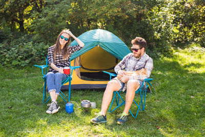 Full length of young couple sitting on land