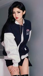 Portrait of young woman standing against wall